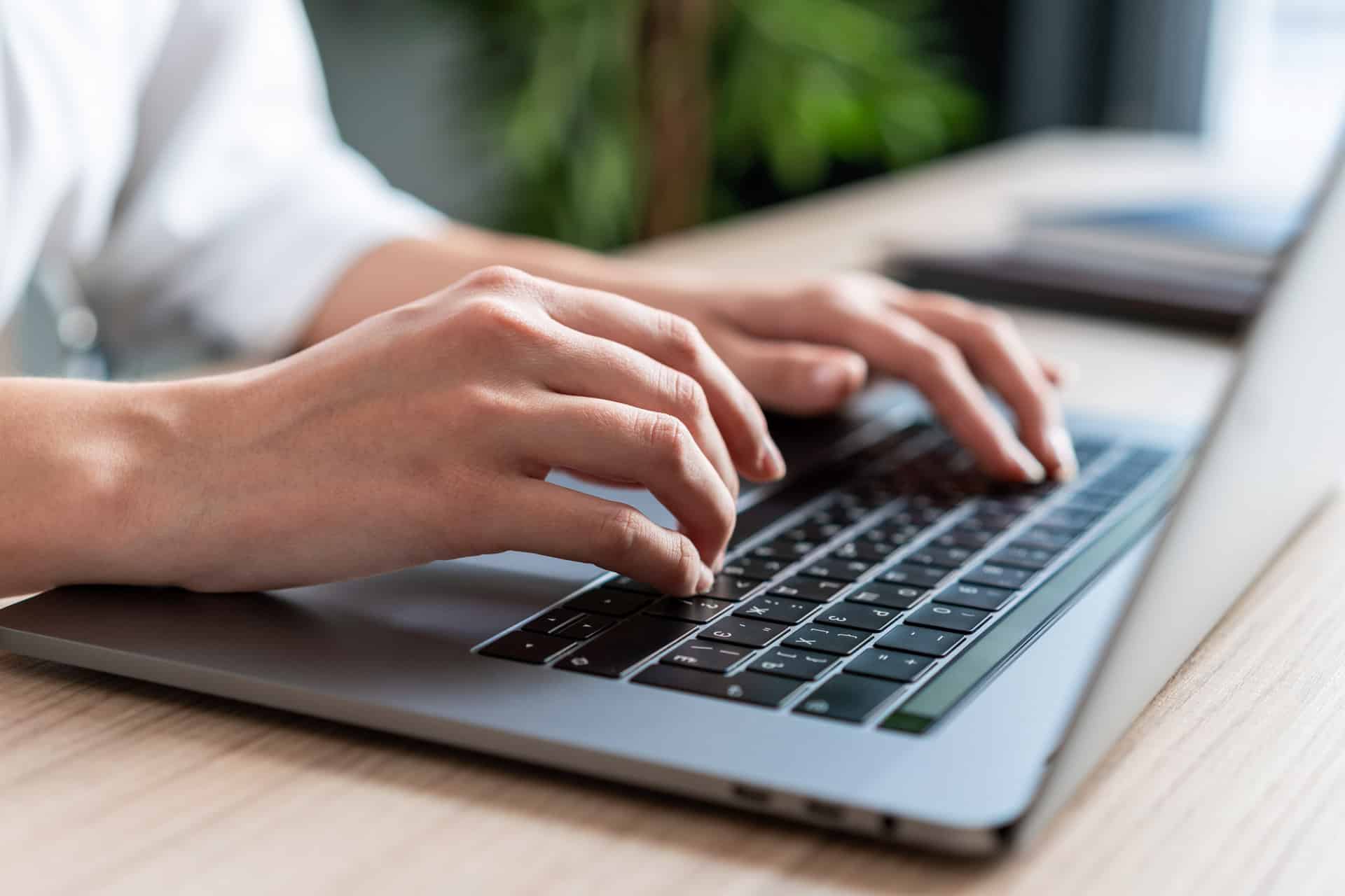 Hender som skriver på laptop